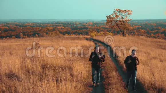 人们在大自然中旅行秋天的生活方式走在路上冒险慢动作视频两个徒步旅行者视频的预览图