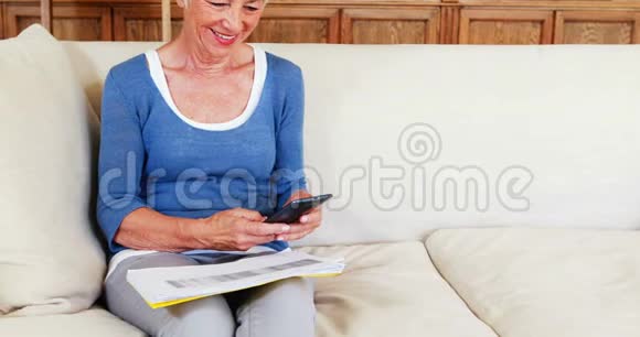 在客厅里使用手机的老妇人视频的预览图
