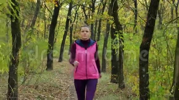 跑步女子跑步者在秋天的森林小径上慢跑适合女性运动健身模特运动员跑步训练视频的预览图
