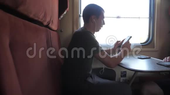 火车车厢里的一个男人听着耳机里的音乐在送信者社交中留言的剪影视频的预览图