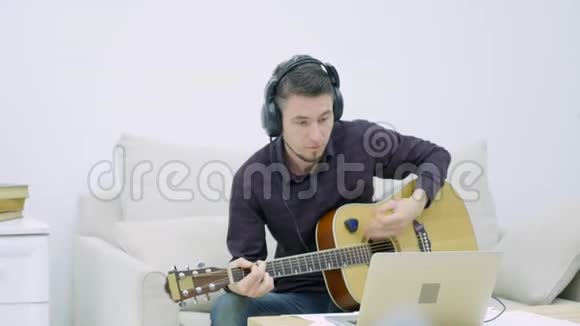 坐在沙发上弹吉他的年轻人视频的预览图