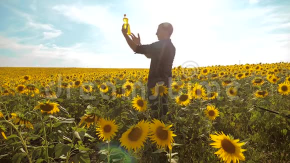 男子农民手捧一瓶葵花籽油在夕阳下的生活方式农民农业塑料瓶视频的预览图