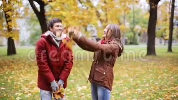 快乐的年轻夫妇在公园里扔秋叶视频的预览图