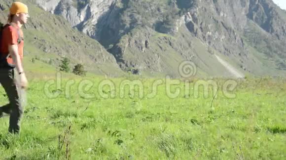 徒步旅行者带着背包在绿色的山地草地上行走夏季运动和娱乐理念视频的预览图