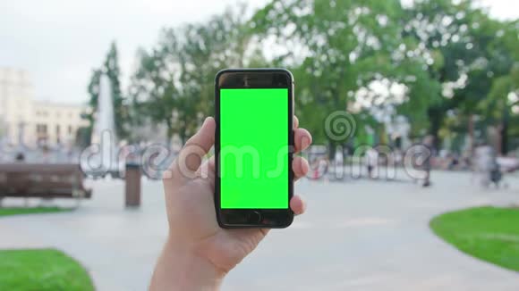 一只手拿着绿色屏幕的手机视频的预览图