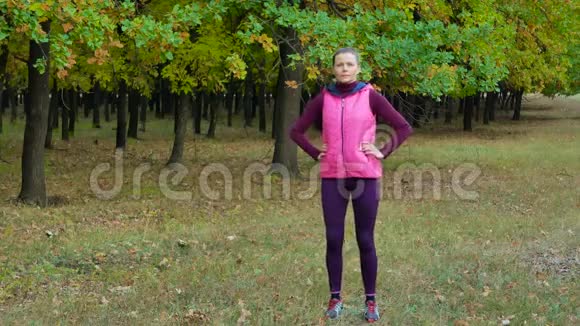美丽的健身运动女孩在秋季公园跑步前热身户外健身视频的预览图
