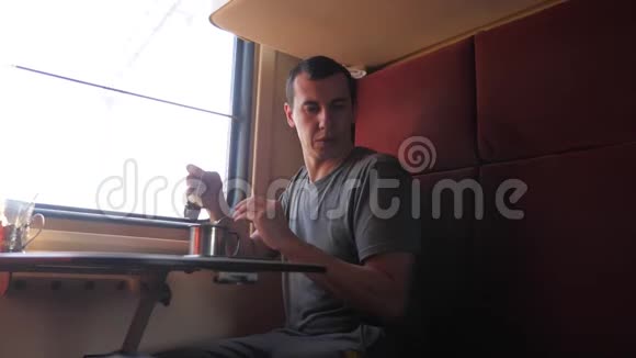 男人坐在火车车厢里手里拿着咖啡和茶慢动作视频男人在喝茶视频的预览图