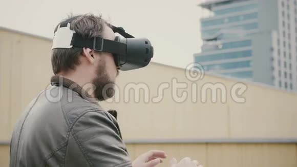 长胡子的帅哥在屋顶上使用虚拟现实眼镜4k视频的预览图