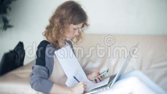 年轻漂亮的女商人坐在沙发上桌上放着平板电脑看着报纸视频的预览图