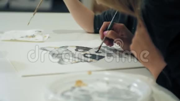 孩子们女孩坐在教室的桌子旁用手指和油漆画画带着他们视频的预览图