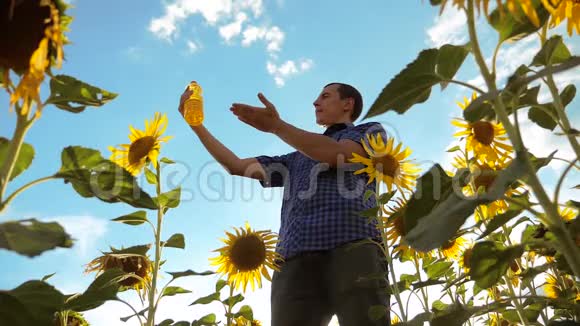 农夫手里拿着一个塑料瓶向日葵油立在田野里慢动作视频生活方式向日葵视频的预览图