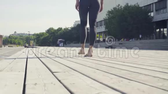 一位年轻女子赤脚走在木地板上视频的预览图