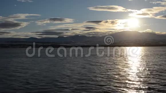 美丽的日落覆盖了北极圈的雪山蓝天和平静的海浪视频的预览图