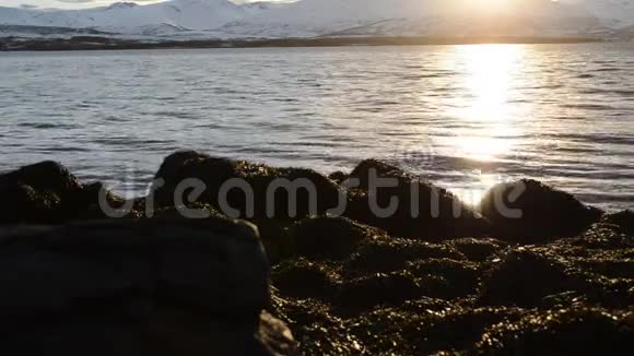 美丽的日落覆盖了北极圈的雪山蓝天和平静的海浪视频的预览图