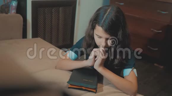 小女孩用手中的圣经祈祷天主教神圣的圣经儿童和视频的预览图