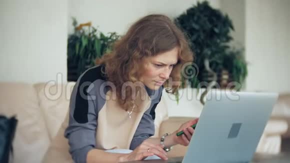 年轻漂亮的女商人坐在沙发上桌上放着平板电脑视频的预览图
