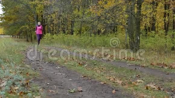 慢速跑步女子跑步者在秋天的森林小径上慢跑适合女性运动健身模特运动员跑步视频的预览图