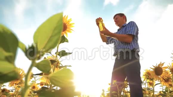 农夫老人手里拿着一个塑料瓶向日葵油立在田野里慢动作视频向日葵视频的预览图
