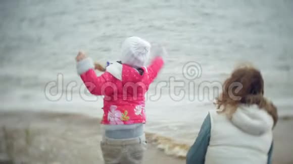 幸福美丽的母女在河岸的沙滩上喂海鸥视频的预览图