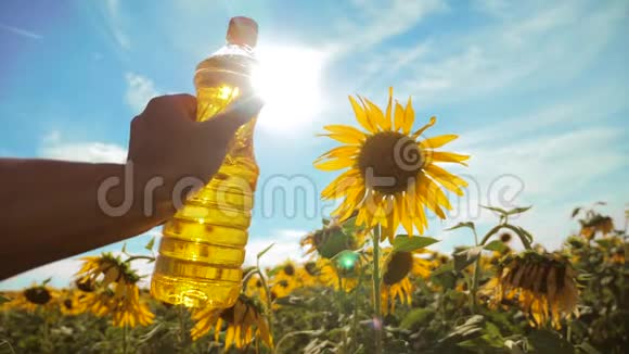 农夫手里拿着一瓶塑料葵花籽油阳光洒在他的手里慢动作视频蓝天背景视频的预览图