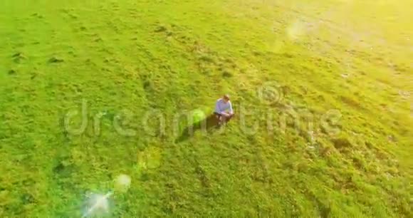 超高清4k鸟瞰图低轨道飞行超过商人坐在草地上带笔记本垫在野外视频的预览图
