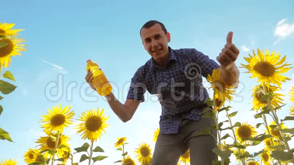 男人手里拿着一个生活方式塑料瓶葵花油站在田野里慢速视频视频的预览图