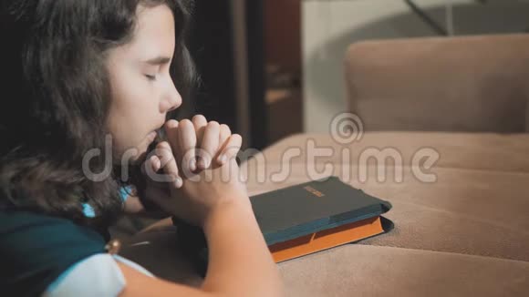 小女孩在夜里祈祷小女孩用手祈祷小女孩圣经祈祷与圣经在她的手中a视频的预览图