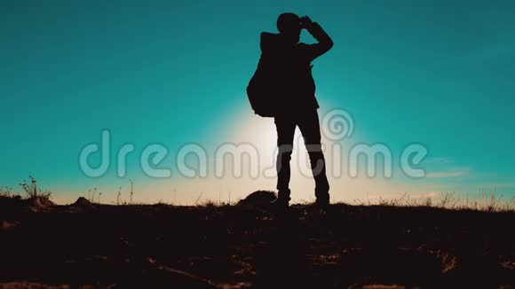 带狗的男游客站在山顶上智能手机导航人在日落时的剪影徒步旅行者冒险视频的预览图