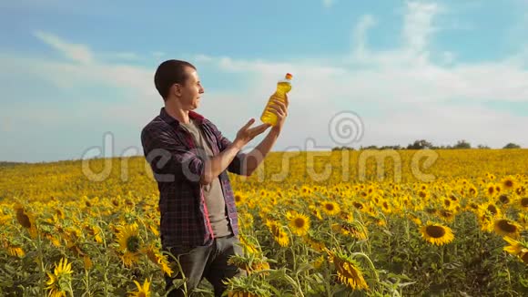 日落时分农夫手捧一瓶葵花籽油农民农业塑料瓶葵视频的预览图