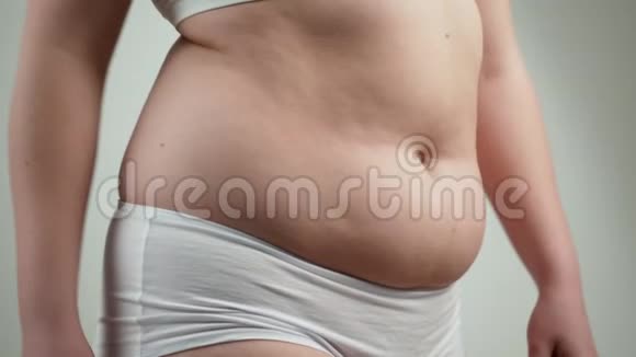 穿白色内衣的女人抱着她的腹部脂肪视频的预览图