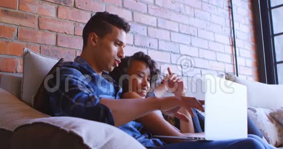 一对夫妇在家里的沙发上用笔记本电脑视频的预览图