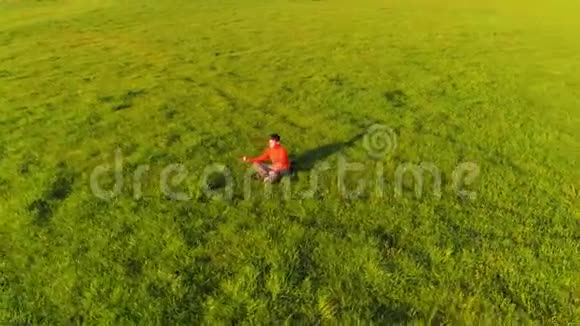 低空径向飞行超过运动瑜伽男子在完美的绿草在山上日落视频的预览图