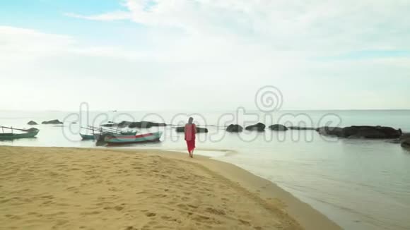 穿着红衣服的女人在海滩上散步视频的预览图