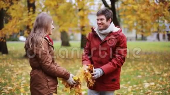 快乐的年轻夫妇在公园里扔秋叶视频的预览图