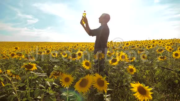 农夫手捧一瓶葵花籽油夕阳西下的田野生活方式农民农业塑料瓶视频的预览图