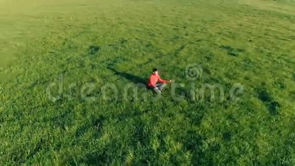 低空径向飞行超过运动瑜伽男子在完美的绿草在山上日落视频的预览图