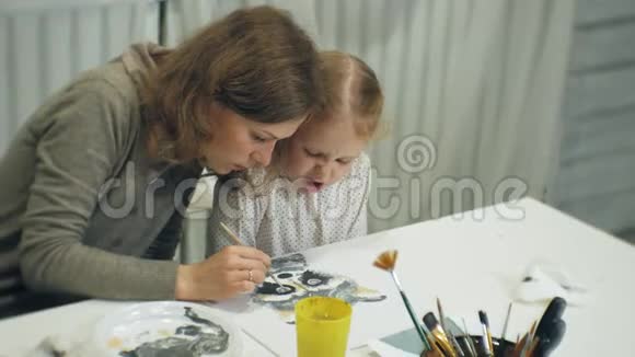 孩子们女孩坐在教室的桌子旁用手指和油漆画画带着他们视频的预览图
