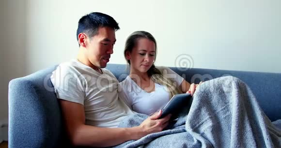 情侣在沙发上放松时使用数码平板电脑视频的预览图