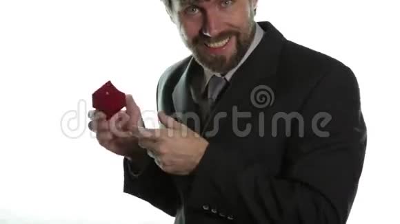 穿着商务服的大胡子男人在红盒子里戴上戒指表达不同的情感视频的预览图