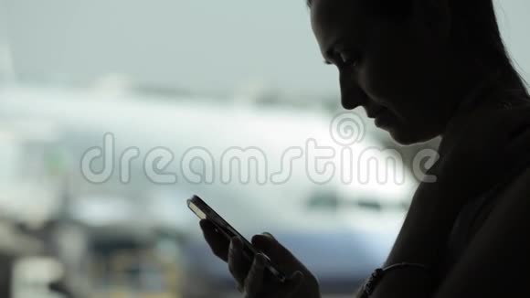 年轻女子在机场带着智能手机背景是飞机视频的预览图