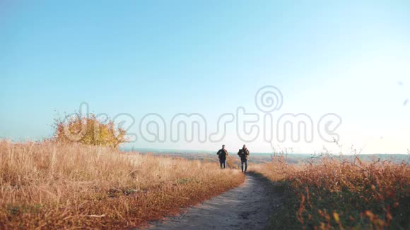 两个男人的生活方式旅行者带着背包徒步旅行沿着爬山的小路走着慢动作视频的预览图