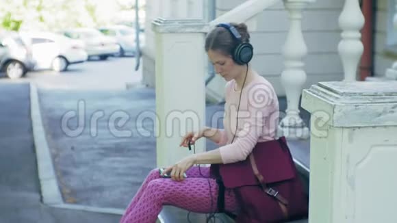 年轻时尚的美女在城市街道上听音乐的大监控耳机视频的预览图
