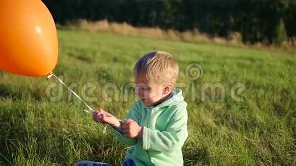 可爱的男孩站在田里拿着气球视频的预览图