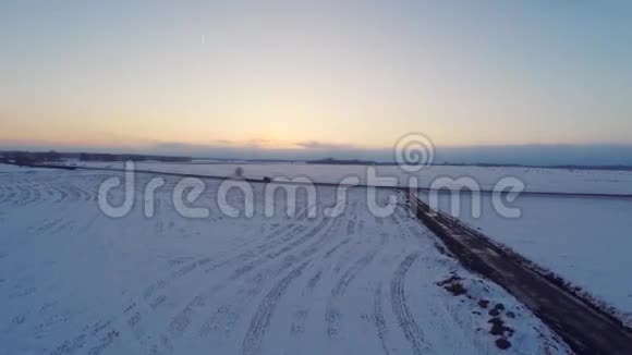 冬天的路空中镜头白雪覆盖的白田日落视频的预览图