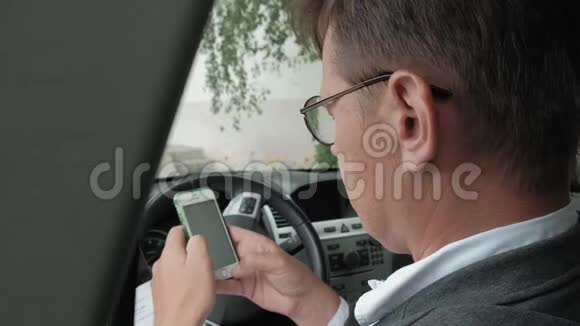 成熟的汽车商人使用智能手机视频的预览图