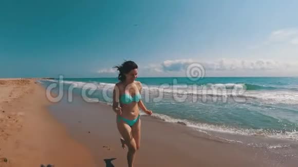小女孩沿着海岸海滩慢动作奔跑视频的预览图