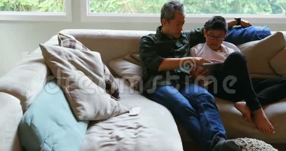 父亲和儿子使用4k客厅的数字平板电脑视频的预览图