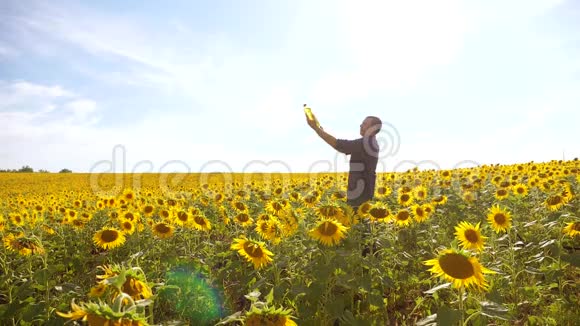 日落时分农夫手捧一瓶葵花籽油男人展示了葵花籽油的生产视频的预览图