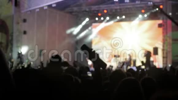 音乐音乐会上的人群在明亮多彩的舞台灯光前成群的观众在智能手机上拍照视频的预览图