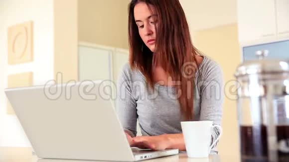 穿着笔记本电脑坐着喝咖啡的深黑色美女视频的预览图